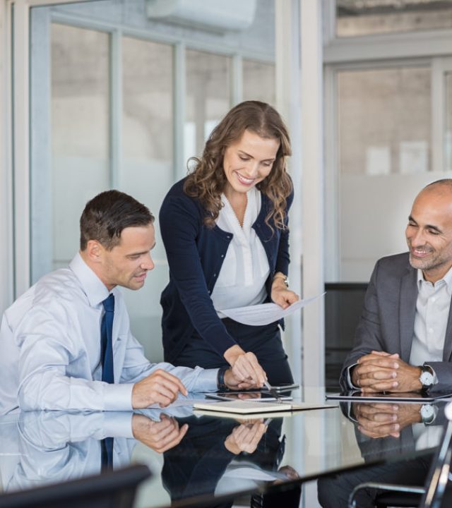 Smiling business team working together on a project in a modern Smiling business team working together on a project in a modern conference room. Happy business partners planning work at meeting. Successful business people group working in modern office.